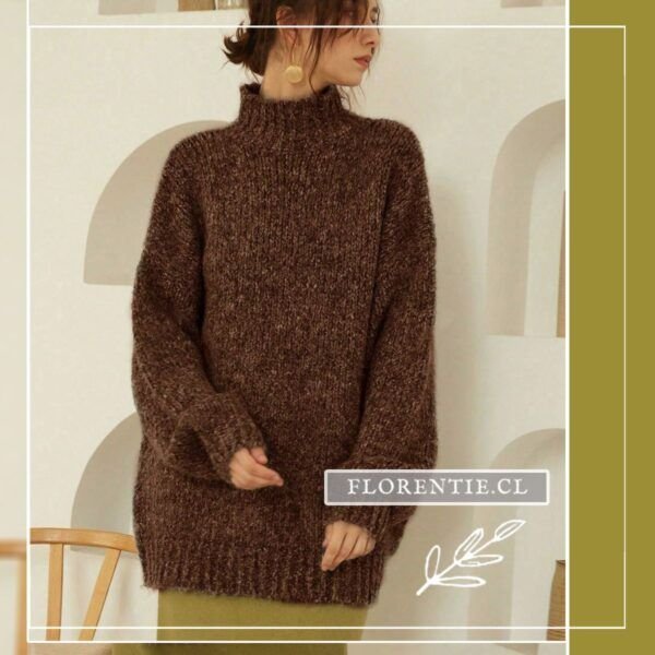 Vista frontal del chaleco oversize café chocolate con cuello tortuga de punto grueso esponjoso y mangas amplias con puños acanalados, en interior minimalista con nichos blancos.