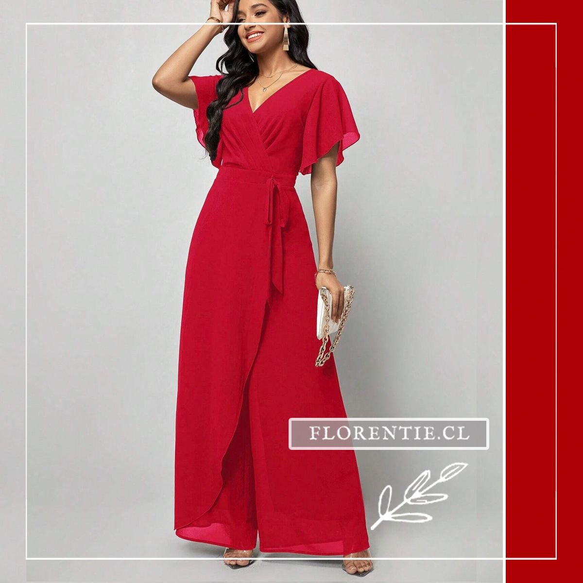 Mujer con enterito largo rojo carmín de fiesta con escote V cruzado, mangas flutter fluidas, cinturón de lazo y falda-pantalón palazzo de abertura frontal estilizadora