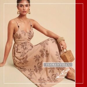 Modelo sentada luciendo vestido largo boho con patrón botánico en tonos tierra, escote V con fruncido y tirantes de cuentas, sosteniendo bolso de rattan, estilo romántico relajado.