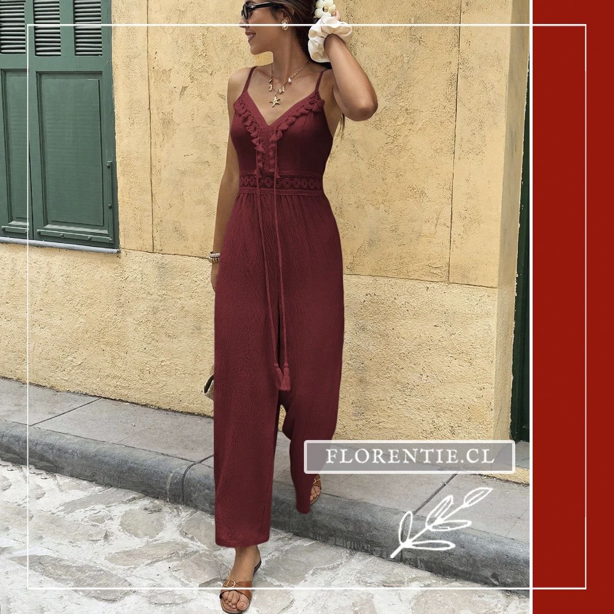 Mujer apoyada en pared luciendo el enterito burdeo Isabella con tirantes ajustables, ribetes de borlas en escote V y panel de encaje calado tipo crochet en cintura