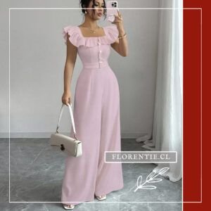 Mujer con enterito rosado Pau y bolso blanco, luciendo el escote cuadrado con volantes, botones de perla y cinturón metálico que define la cintura antes del palazzo