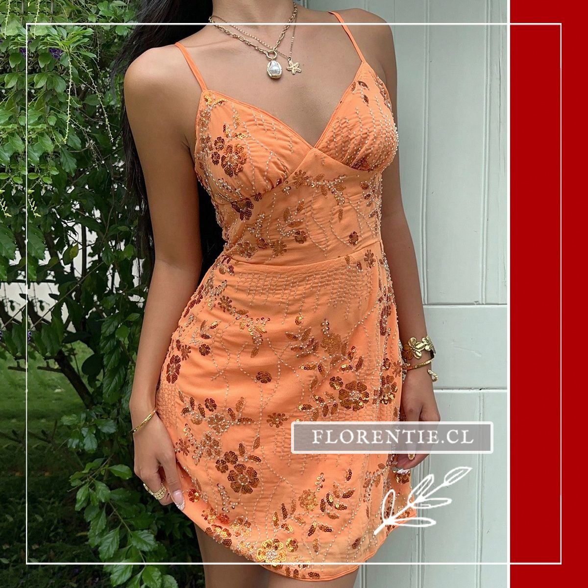 Vista frontal completa del vestido corto naranja con bordado floral en lentejuelas y abalorios brillantes, silueta ceñida entallada y escote V estructurado, posando en exterior con vegetación.